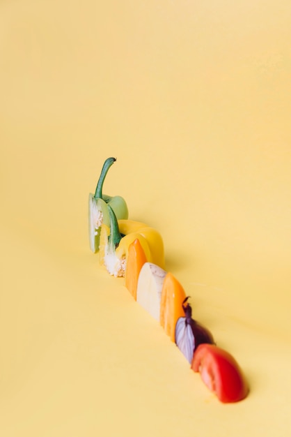 Bezpłatne zdjęcie rząd różnorodni kolorowi warzywo plasterki na kolor żółty powierzchni