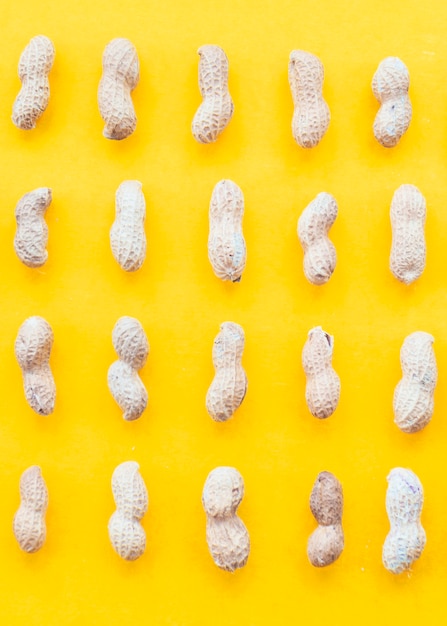 Bezpłatne zdjęcie rząd surowi arachidy na żółtym tle