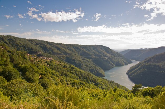Rzeka Minho otoczona wzgórzami pokrytymi zielenią w słońcu w Hiszpanii