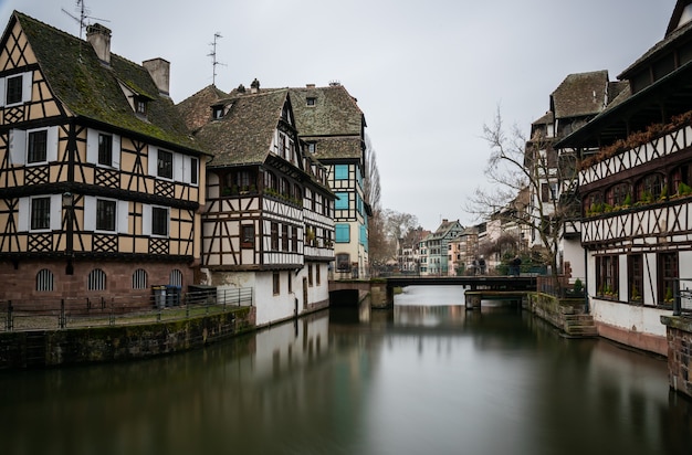 Rzeka otoczona budynkami w Petite France pod zachmurzonym niebem w Strasburgu we Francji