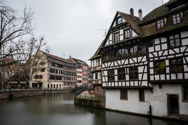 Rzeka otoczona kolorowymi budynkami i zielenią pod zachmurzonym niebem w Strasburgu we Francji