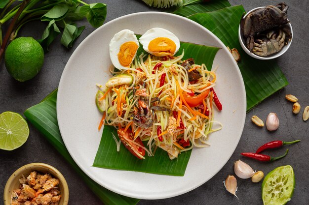 Sałatka z papai podana z makaronem ryżowym i sałatką warzywną Udekorowana tajskimi składnikami żywności.
