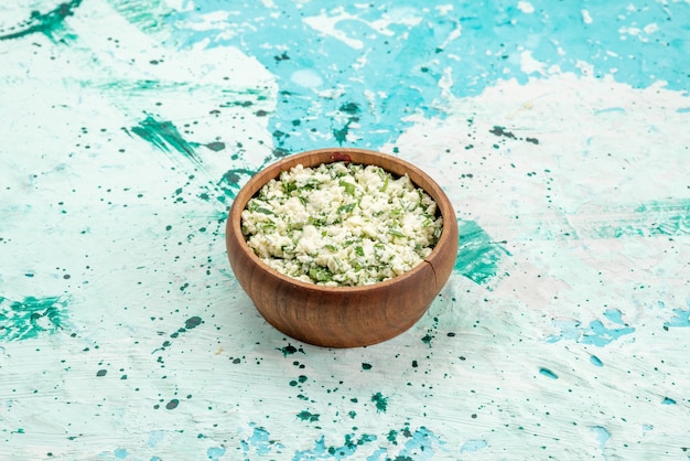 Bezpłatne zdjęcie sałatka ze świeżej pokrojonej kapusty z zieleniną w brązowej misce na jasnoniebieskim tle