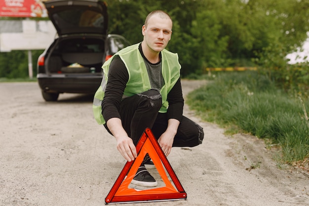 Samochód z problemami i czerwony trójkąt ostrzegający innych użytkowników drogi