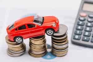 Bezpłatne zdjęcie samochód z zabawkami balansujący nad rosnącym stosem monet