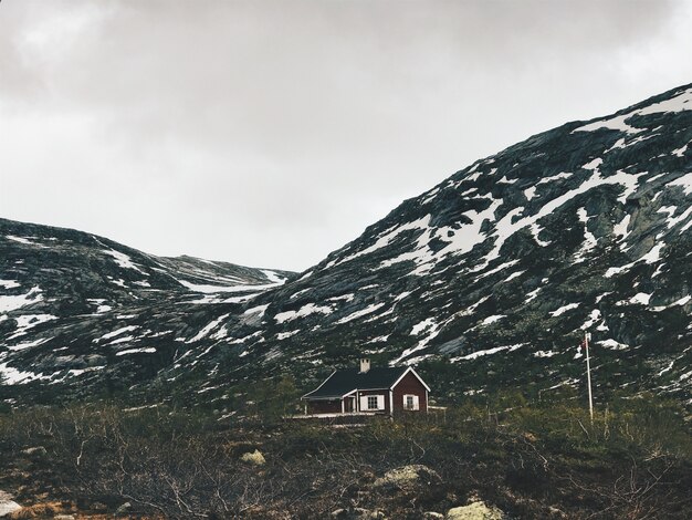 Samotna kabina stoi przed górami pokryty śniegiem