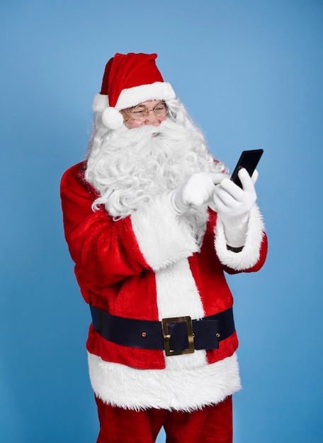 Bezpłatne zdjęcie santa claus za pomocą telefonu komórkowego w studio strzał