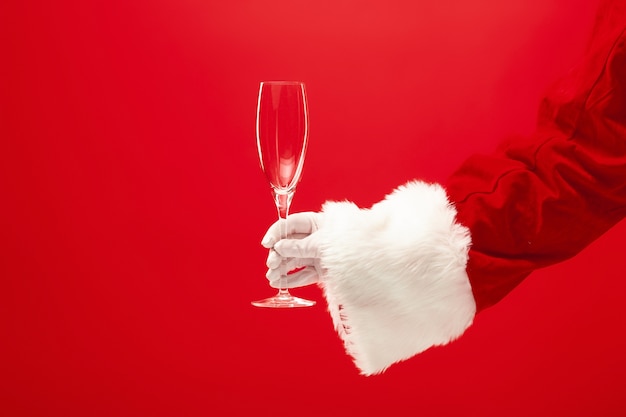 Santa Holding Champagne wineglass na czerwonym tle. sezon, zima, wakacje, uroczystość, koncepcja prezentu