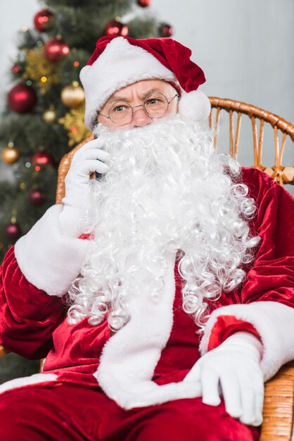 Santa siedzi na bujanym fotelu i rozmawia przez telefon
