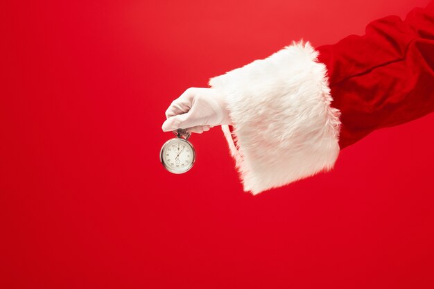 Santa trzyma stoper na czerwonym tle. sezon, zima, wakacje, uroczystość, koncepcja prezentu