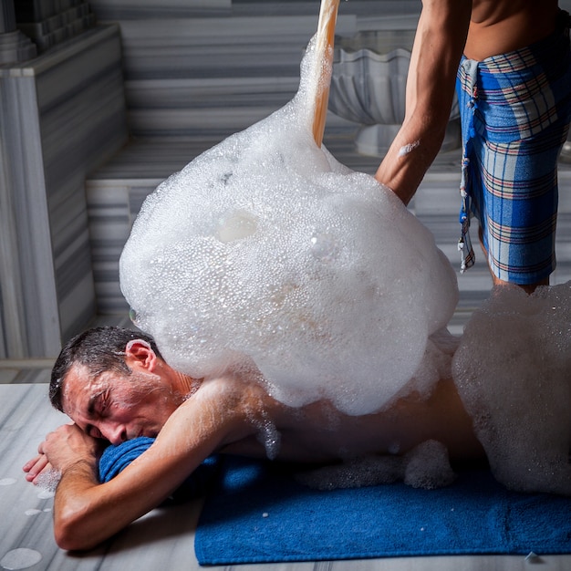 sauna turecka z klientem i pianą oraz ludzką ręką na wannie