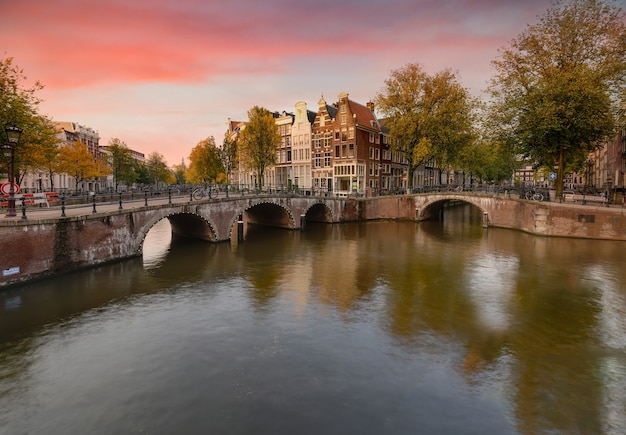 Sceneria kanału Keizersgracht w Amsterdamie z odbiciami budynków i zielonych drzew