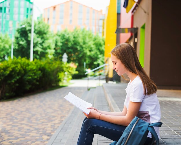 Schoolgirl czytanie książki na kroki