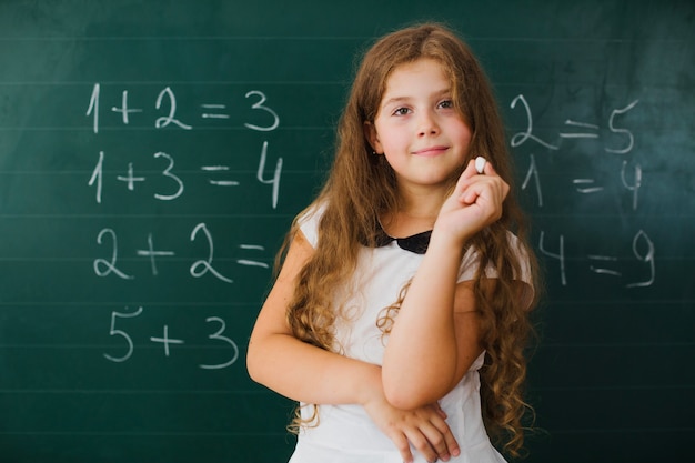 Schoolgirl uśmiecha się na tablica w klasie