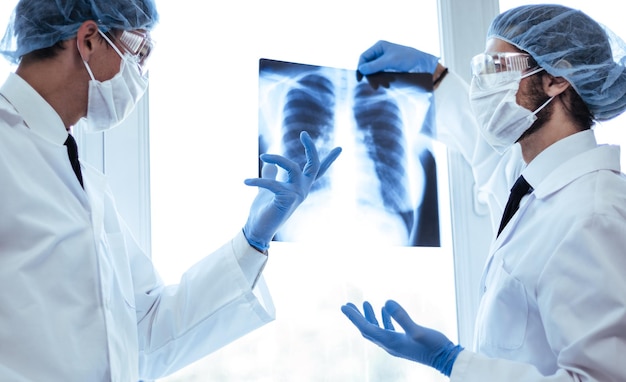 Ścieśniać. naukowcy w maskach ochronnych patrzący na prześwietlenie płuc . koncepcja opieki zdrowotnej.