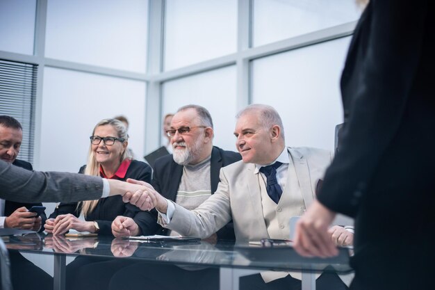 Ścieśniać. partnerzy biznesowi, ściskając ręce przy stole negocjacyjnym. koncepcja współpracy