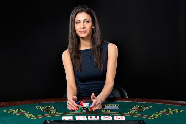 Seksowna kobieta z kartami do pokera i żetonami. Zawodniczka w pięknej czarnej sukience