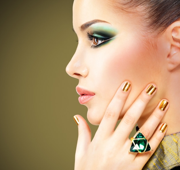 Bezpłatne zdjęcie seksowny dama z pięknymi złotymi paznokciami i szmaragdowym pierścieniem na rękach