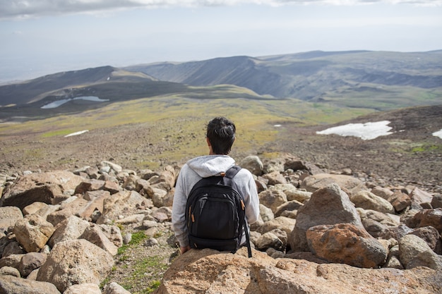 Selektywne fokus strzał osoby siedzącej na skale z pięknym widokiem na góry