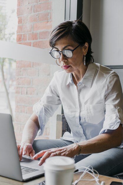 Senior z eyeglasses pracuje na laptopie