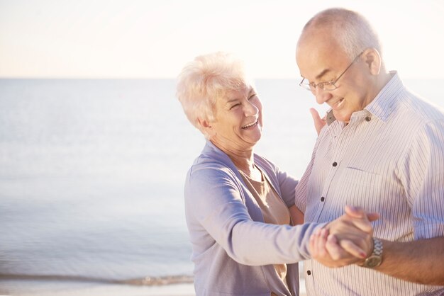 Seniorzy tańczą na plaży w świetnych nastrojach