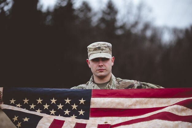 Shallow fokus strzał amerykańskiego żołnierza trzymającego amerykańską flagę