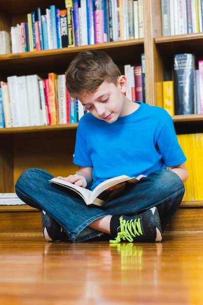 Siedzi na podłodze podekscytowany chłopiec czytanie książki