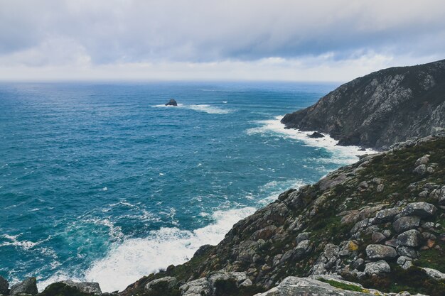 Skaliste urwisko Cape Finisterre w Galicji w Hiszpanii pod pochmurnym niebem