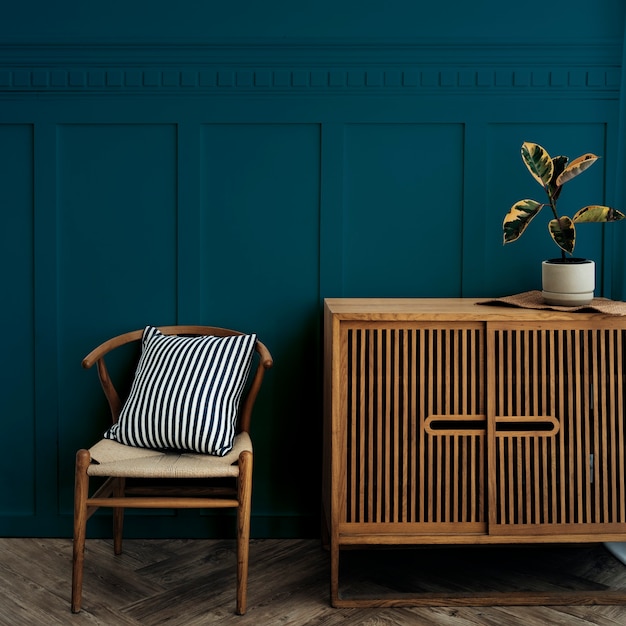 Skandynawska szafka z drewna w stylu vintage z krzesłem przy ciemnoniebieskiej ścianie