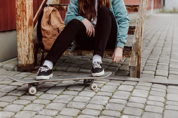 Bezpłatne zdjęcie skater dziewczyna w miejskich siedząc na schodach widok z przodu