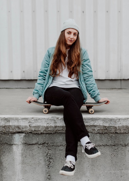 Skater dziewczyna w miejskich siedzi na łyżwie