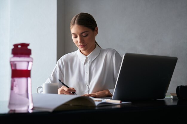 Skoncentrowana kobieta pracująca na laptopie podczas pobytu w domu