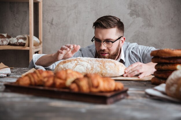 Skoncentrowanego mężczyzna piekarniana pozycja przy piekarnią blisko chleba