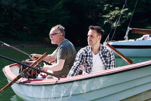 Skoncentrowani mężczyźni z wędką siedzący na łodzi