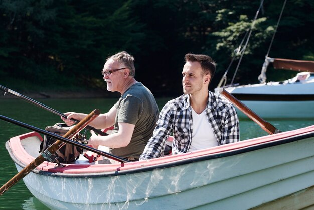 Skoncentrowani mężczyźni z wędką siedzący na łodzi