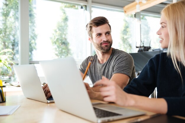 Skoncentrowani młodzi koledzy siedzi w biurowym coworking