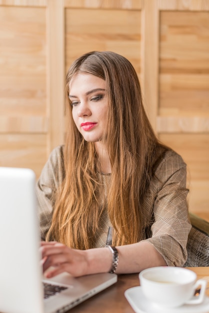 Bezpłatne zdjęcie skoncentrowany kobieta, patrząc na ekranie swojego laptopa