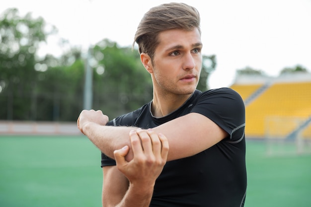 Skoncentrowany Męski Sportowiec Wykonuje ćwiczenia Rozciągające Na Zewnątrz