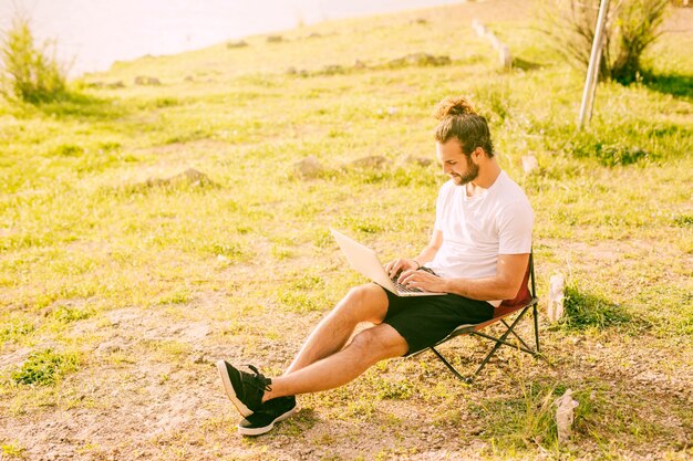 Skoncentrowany modniś pracuje z laptopem outdoors