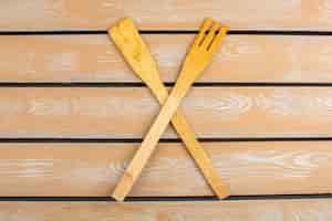 Bezpłatne zdjęcie skrzyżowane narzędzia kuchenne drewniane wykonane na jasnym tle