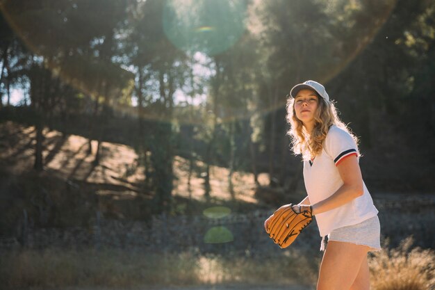 Skupiająca się młoda kobieta bawić się baseballa