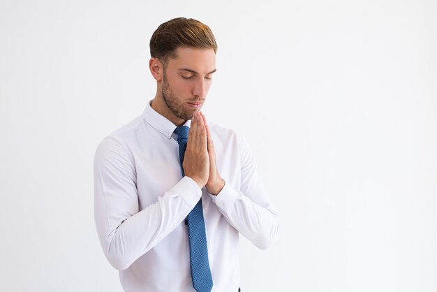 Skupiający się biznesowy mężczyzna ono modli się i utrzymuje ręki wpólnie.