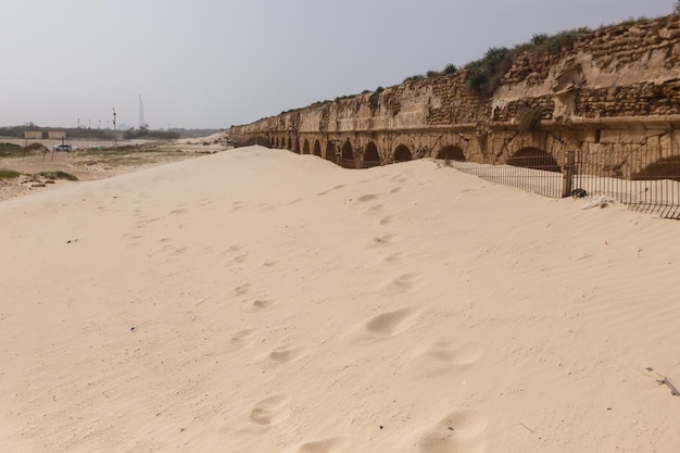 Ślady stóp na piasku obok akweduktu w cezarei