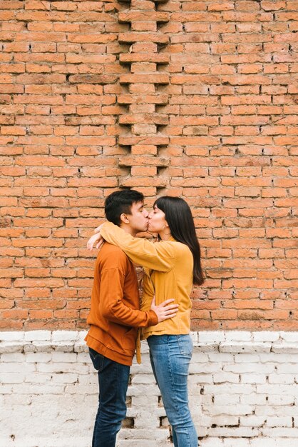 Śliczna całowanie pary pozycja na tle ściana z cegieł