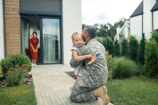 Śliczna Delikatna Dziewczyna. Oficer Wojskowy Czuje Się Niezapomniany, Przytulając Swoją Uroczą, Czułą Dziewczynę, Wracając Do Domu Premium Zdjęcia