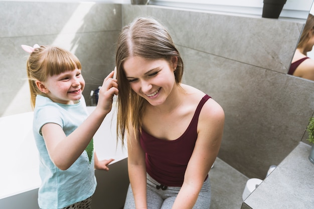 Bezpłatne zdjęcie Śliczna dziewczyna pomaga matki rozczesać włosy