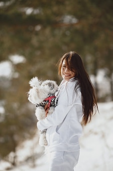 Śliczna dziewczyna spaceru w winter park. kobieta w brązowej kurtce. pani z psem.