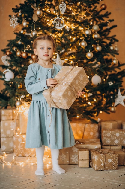 Śliczna dziewczyna stojąca z prezentami świątecznymi przy drzewie