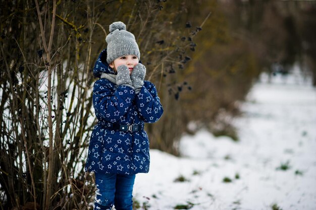 Śliczna mała dziewczynka bawi się na świeżym powietrzu w zimowy dzień