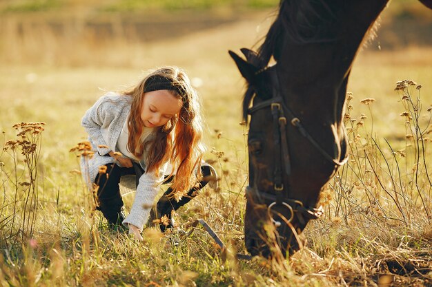Śliczna mała dziewczynka w jesieni polu z koniem